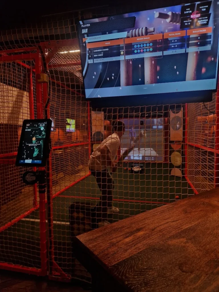 GC Reports team-building event: An engineer participating in an interactive cricket simulator during an industry social outing