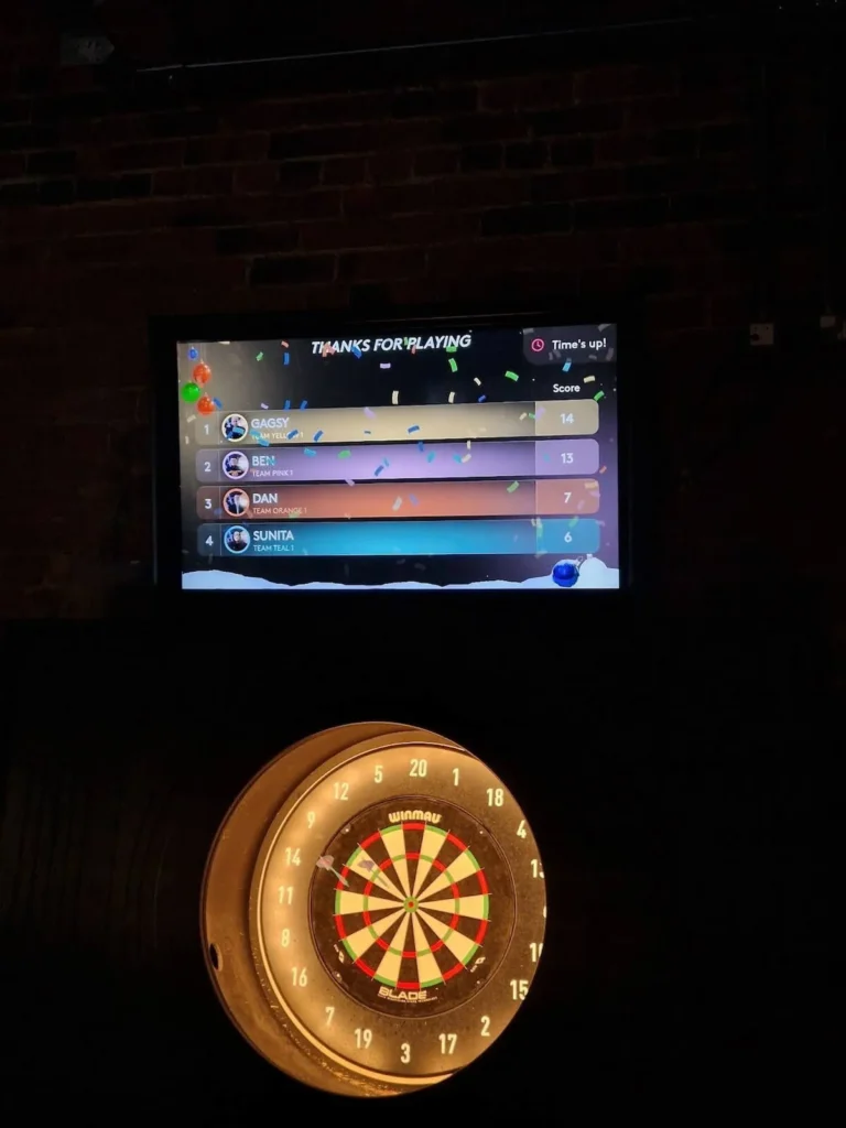 GC Reports team social event: An interactive digital darts scoreboard and Winmau dartboard during a team-building trip