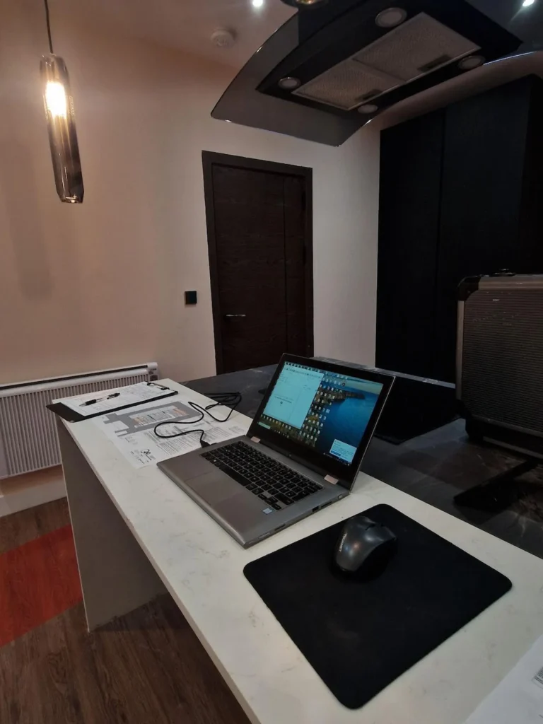 Professional acoustic analysis workstation featuring a laptop, floor plans, and measurement software for Building Regulations Part E verification